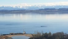 vast lake with clear blue water, mountain range in the background, small dock, ripples