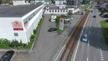 White building with signage, multiple cars parked in parking lot, road with vehicles