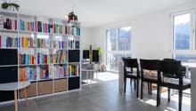 Dining area with a large bookshelf, dining table, chairs, and a view of the mountains