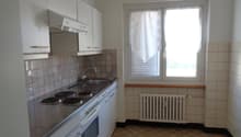 Compact kitchen with white cabinets, tiled backsplash, electric stove, dishwasher, and washing machine. The kitchen has a window providing natural light.
