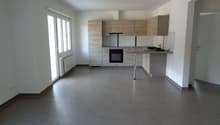 Empty kitchen with tiled floor, wooden cabinets, white walls, large windows, and a countertop with a sink and faucet.