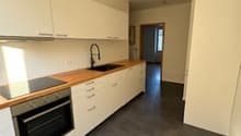 modern kitchen with white cabinets, wooden countertops, black floor, integrated oven, dishwasher, washing machine