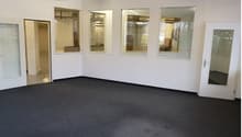 empty room with two entrances, windows, carpet, bright fluorescent lighting