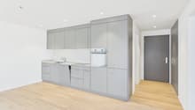 modern kitchen with integrated oven and sink, gray cabinetry, wooden floors, spacious, no appliances seen