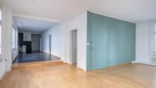 empty room with wooden floors, white and green walls, radiators, and multiple windows