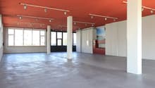 Empty room with red ceiling, white walls, concrete floor, large windows, and track lighting.