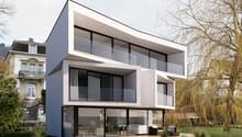 Modern two-story house with a flat roof, large windows, and a swimming pool in the backyard. The house has a balcony or terrace on the upper level.
