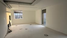 Empty room with white walls and floors, sliding door, two windows, pipes on the ceiling