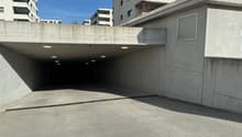 Concrete underground parking with several ceiling lights, entrance ramp and drainage system