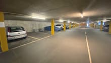 concrete floor, yellow pillars, multiple cars parked, empty spaces
