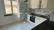 modern kitchen with white cabinets, tile floor, black countertop, built-in oven and refrigerator, sink with faucet, and a window