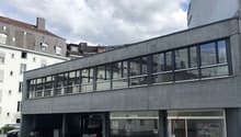 2 story building with large windows, car park in front, cars parked inside