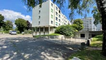Residential building with several windows and a parking area at the front