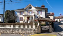 2 story house, multiple windows, balcony, stone fence, gate, no visible garage or pool