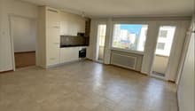 Empty room with tiled floor, white walls, kitchen area with sink, oven, and cabinets, sliding glass doors, and windows