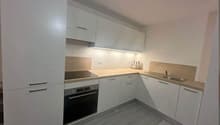 modern kitchen with white cabinets, wooden countertops, integrated oven and dishwasher, sink with faucet, power outlets