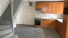 empty kitchen with wooden cabinets, tiled floor, white walls, staircase