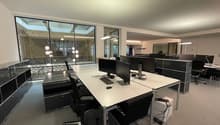 modern office space with desk, chairs, computers, large windows, tiled floor, lamps
