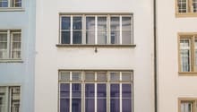 3 story building, glass windows, glass entrance with 'Orsay' text, street lamp, brick paved street