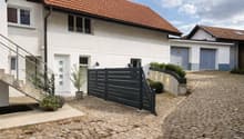 white house, brown roof, black gate, brick driveway, stairs, plants