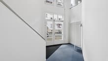 White walls, blue carpet, white radiator, glass doors, metal handrail