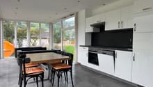 dining area with a wooden table and chairs, white cabinets, black countertops, oven, dishwasher, glass windows