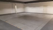 Empty parking lot, white walls, gray floor, white ceiling, yellow line markings, pillar