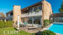 Modern house with brick facade, large windows, balcony, outdoor dining area, swimming pool, garden