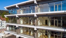 Modern multi-story building with glass facade, balconies, and terraces