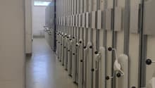 Storage units lined up, with numbers 40-47 on the doors, white walls, metallic beams, and a metal railing.