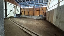 empty room, dirt floor, wooden walls, large open windows, metal roof