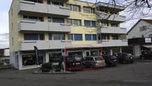 Multi-story building, balconies, yellow exterior, parking lot