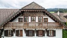 Facade of a chalet with an upper terrace supported by wooden structures and various windows