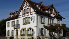 3 story house, white walls, brown roof, brown trim, arched windows, balconies, flower boxes, outdoor seating