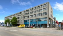 4 story office building with multiple glass windows, yellow van parked in front