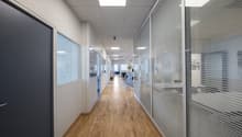 Office hall with wooden floors, glass walls, white walls, modern interior, surveillance camera