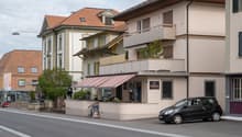 Building with a red awning, balcony, and a car parked in front