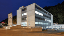 modern office building, white exterior, multiple floors, parking lot in front