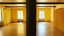 large empty room, wooden floor, yellow walls, windows, radiators