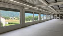 Empty room with large windows, tiled floor, metal ceiling, view of a field and mountains