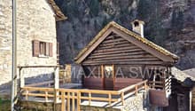 Rustic log cabin house, wooden terrace, stone wall, surrounding mountain