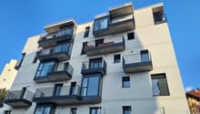 Multi-story apartment building with balconies, modern architectural design, and large windows