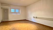 empty room, white walls, wooden floor, radiator, two windows, ceiling light