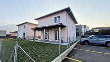 Modern two-story house, white exterior, large windows, bicycle parked in front, fenced area, SUV parked in parking lot