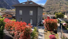2-story house with a tiled roof, surrounded by colorful autumn foliage and landscaped gardens, set against a backdrop of mountains