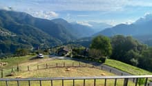panoramic view, green field, mountains, road, houses, fenced area, car parked, clear blue sky