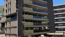 Modern apartment building with multiple floors, balconies, and green plants on the exterior walls