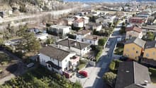Aerial view of multiple houses with red cars parked outside, tiled roofs, driveways, and small gardens with trees