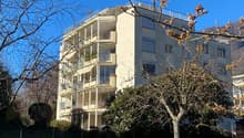 large multistory apartment building with balconies, cream-colored exterior, windows with shutters