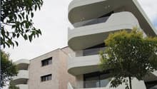 modern apartment building, curved balconies, glass railings, beige ground floor, white upper floors